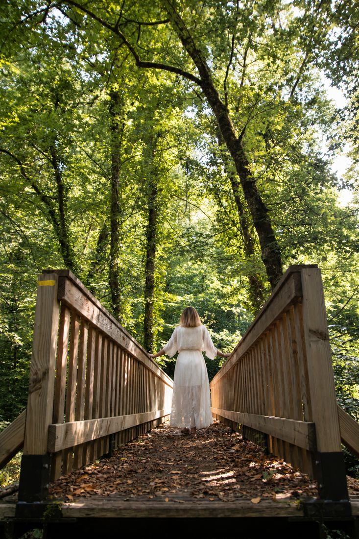Silhouette traversant une passerelle en bois en forêt, chemin symbolique vers l'équilibre intérieur