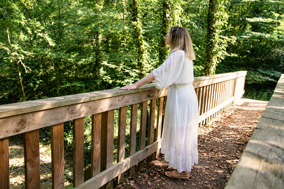 Instant de pleine présence sur une passerelle en forêt, regard levé vers la lumière