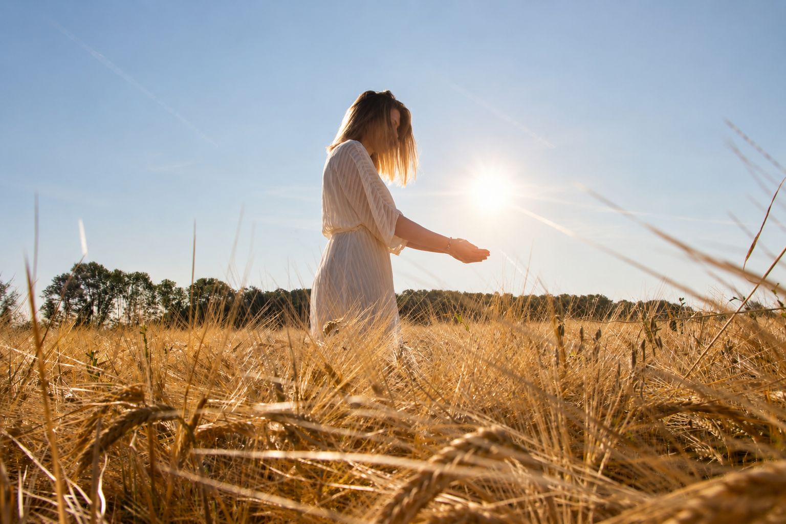Femme en robe blanche traversant un champ de blé au soleil couchant, symbole de sérénité et de reconnexion à soi
